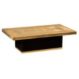 An etched brass coffee table, supported by a black wooden base with a gilt brass edge, signed Ricco