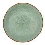 A Chinese celadon-glazed dish, relief decorated with a phoenix and a dragon amongst clouds, the bott