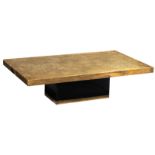An etched brass coffee table, supported by a black wooden base with a gilt brass edge, decorated wit