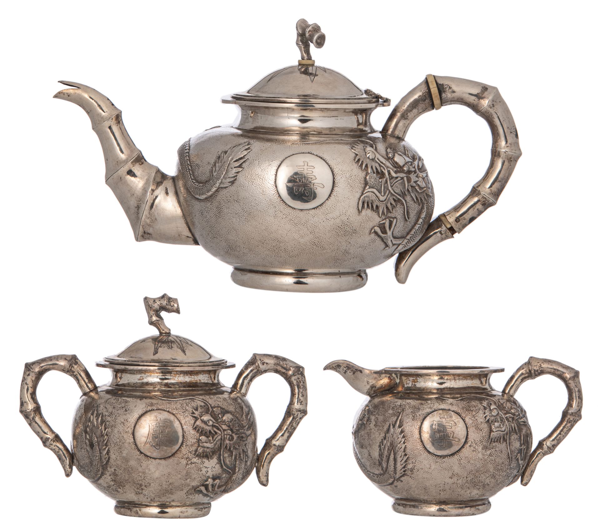 A Chinese three-piece silver tea set with dragon design, marked 'Yok Sang', Shanghai, H 4,5 - W 25,5