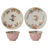 A pair of Chinese relief famille rose and gilt cups and saucers, decorated with squirrels, grapes an