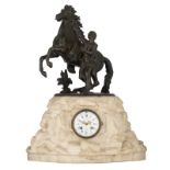 A rock shaped Carrara marble mantel clock, with on top a bronze sculpture of a horse tamer, the dial