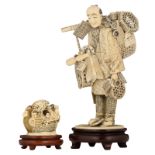 Two Japanese ivory okimono: one depicting a traveling seller, richly decorated with stained engravin