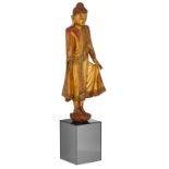 An Oriental gilt decorated wooden standing Buddha statue with semi-precious stone inlay, on a wooden