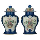A pair of Chinese blue ground vases and covers, the panels famille rose decorated with flowers and f