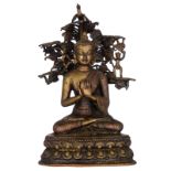 An Oriental bronze seated Buddha, the background with demon figures and a phoenix in a tree, on a lo