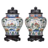 Two Chinese wucai floral decorated vases and hardwood covers, the roundels with animated scenes, wit
