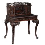 A Chinese exotic hardwood writing desk, richly sculpted with openwork floral decoration, birds and d
