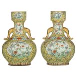 Two yellow ground bottle vases, famille rose decorated with scrolling lotus, the panels with flower