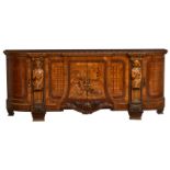 A large richly carved and walnut and mahogany veneered commode flanked by caryatides, the central do