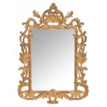 An Italian type wall mirror with a richly and baroque carved, gilt and patinated wooden frame, 78 x