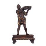 A Japanese gilt decorated bronze group, depicting a fisherman, showing the catch, on a wooden stand,