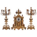 A gilt bronze Baroque inspired three-piece clock garniture, the clock decorated with a trophy on top