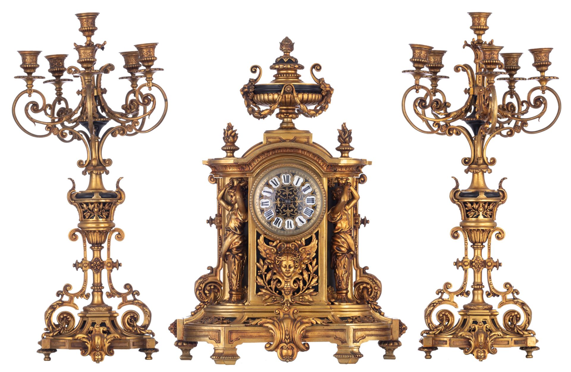 A gilt bronze Baroque inspired three-piece clock garniture, the clock decorated with a trophy on top