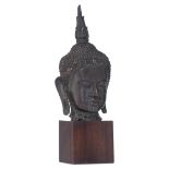 An Oriental bronze group, depicting the head of the Buddha, on a wooden base, H 40,5 cm