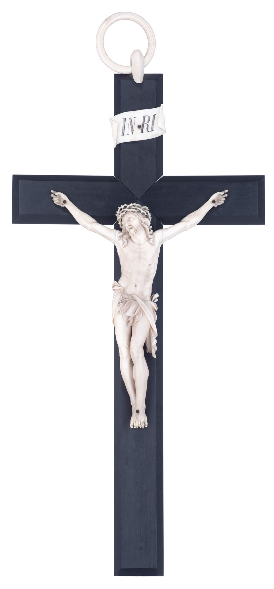 A finely sculpted ivory Corpus Christi on an ebony crucifix with an ivory hanging ring on top, 19thC