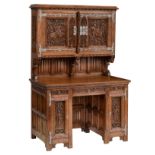 An oak Gothic Revival two-part writing desk, richly sculpted with vines, Gothic pointed arches and l