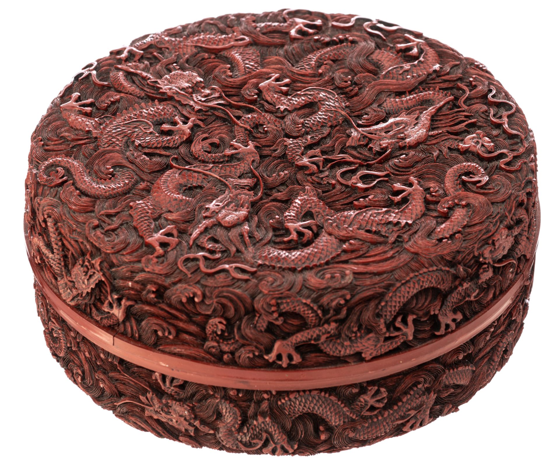 A Chinese style cinnabar red lacquer box and cover, carved with dragons in crashing waves, H 6,5 - ø