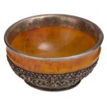 A Tibetan amber bowl with silver mounts, the silver bottom wrought and engraved with a deer in a flo