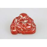 Okimono, Japan, wohl 19. Jh., sitzender Buddha Hotei, roter Stein, H.: ca. 3,5 cm.