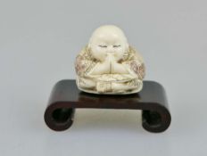 Netsuke, Japan, wohl 19. Jh., kleiner, sitzender Buddha, Elfenbein, am Boden signiert, H.: ca. 3