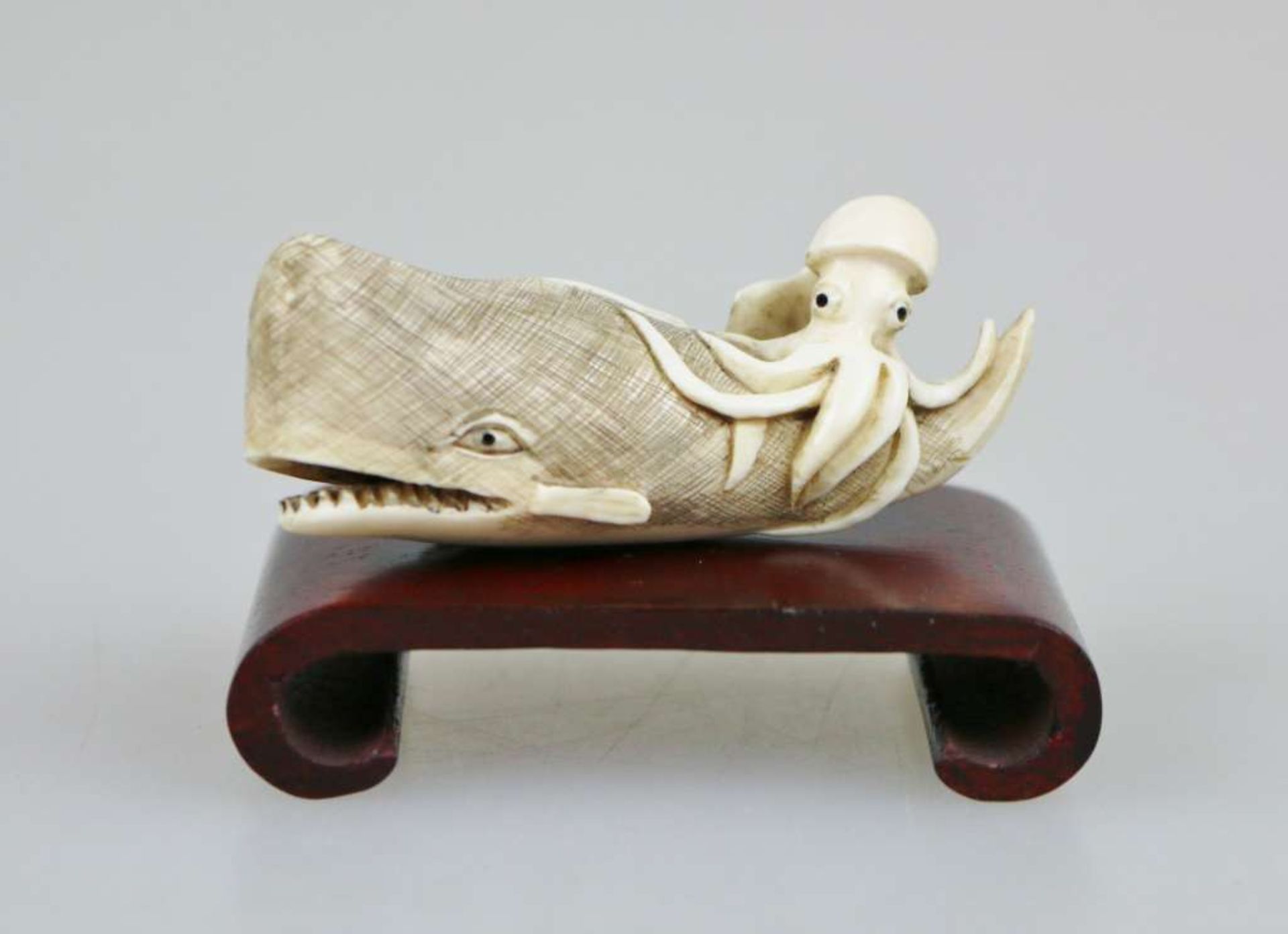 Netsuke, Japan, wohl 19. Jh., Pottwal mit Krake, Elfenbein, am Boden signiert, L.: ca. 6 cm.