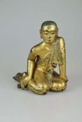 Ananda, Holzfigur mit Lackvergoldung und kleinen Glassteine, wohl Tibet 19./20. Jh., sitzende