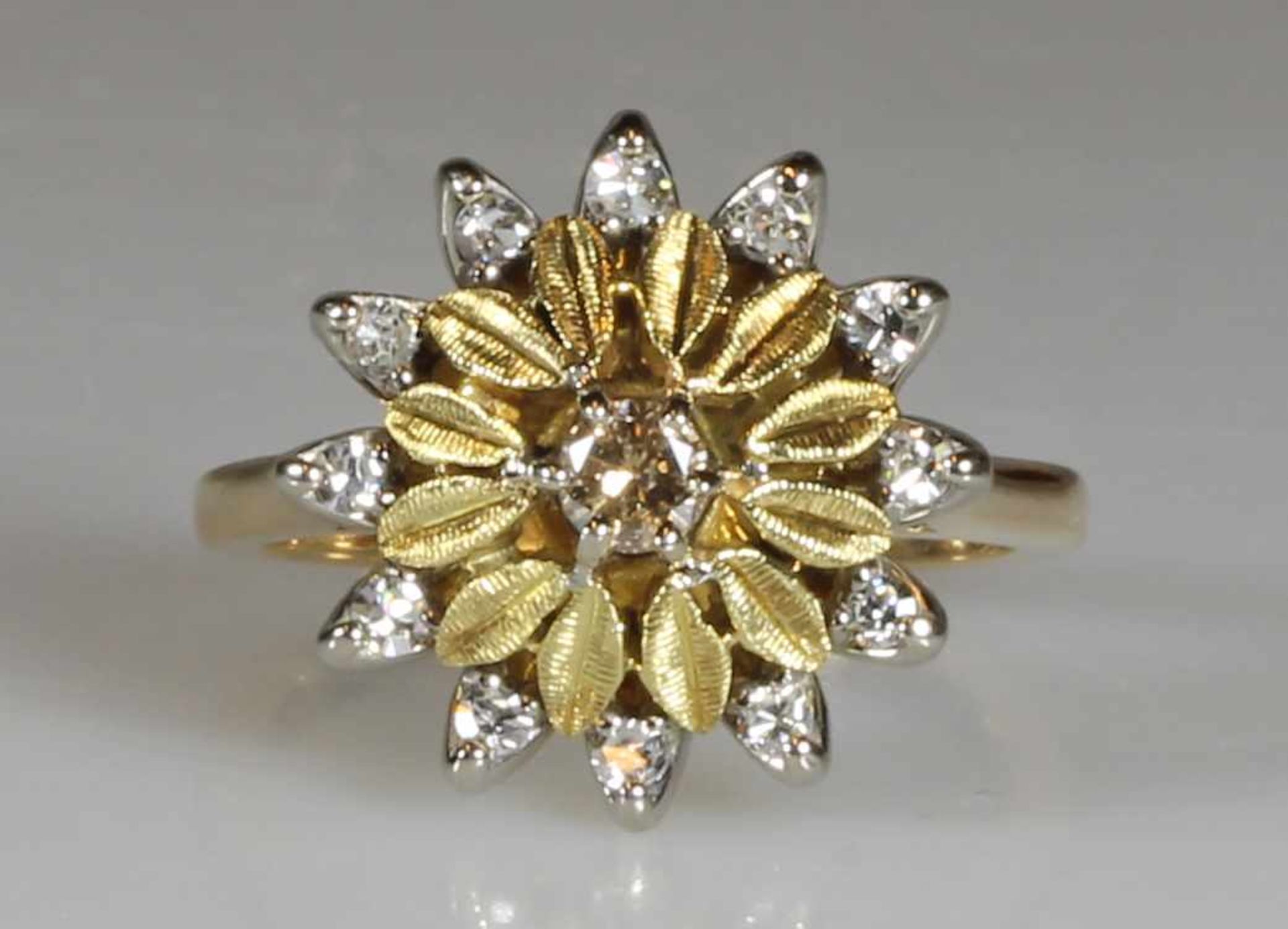 Ring, Blütenform, WG/GG 750, 1 Brillant ca. 0.15 ct., 12 Brillanten zus. ca. 0.24 ct., 6.6 g, RM