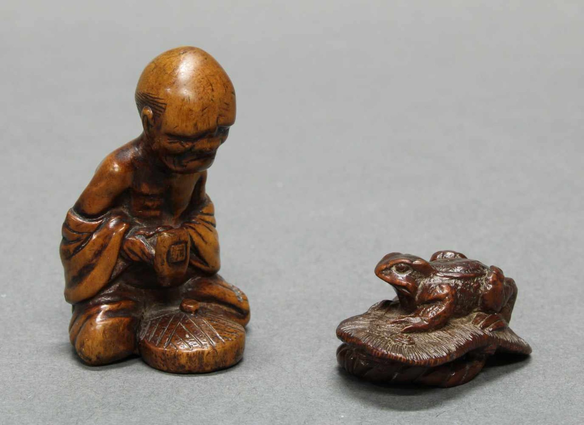 2 Netsuke, "Kröte auf Sandale", "Alter Steinklopfer", Japan, um 1900, Buchsbaum, je Signatur, 2-5 cm