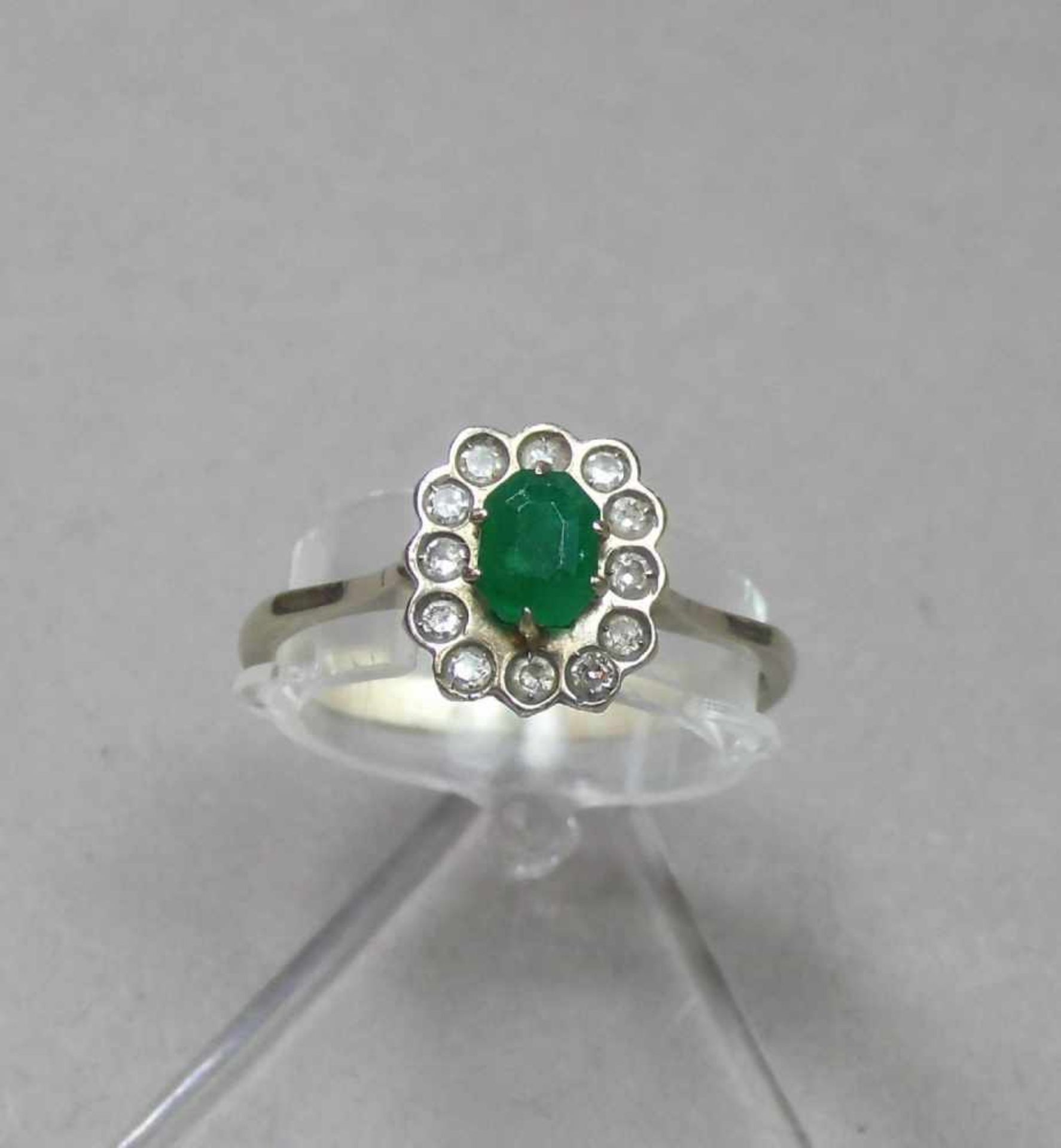 RING, besetzt mit einem ovalen Smaragd, umgeben von einer Vielzahl kleiner Brillanten; 750er