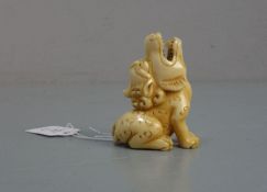 NETSUKE / HANDSCHMEICHLER: Sitzender Fo-Hund oder Drache, Japan, geschnitztes Elfenbein, mit