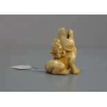 NETSUKE / HANDSCHMEICHLER: Sitzender Fo-Hund oder Drache, Japan, geschnitztes Elfenbein, mit