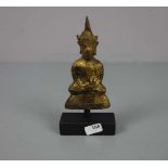 KLEINER BUDDHA AUF HOLZPOSTAMENT, Thailand, 18. Jh., Bronze mit goldfarbener Patinierung. Ein in der