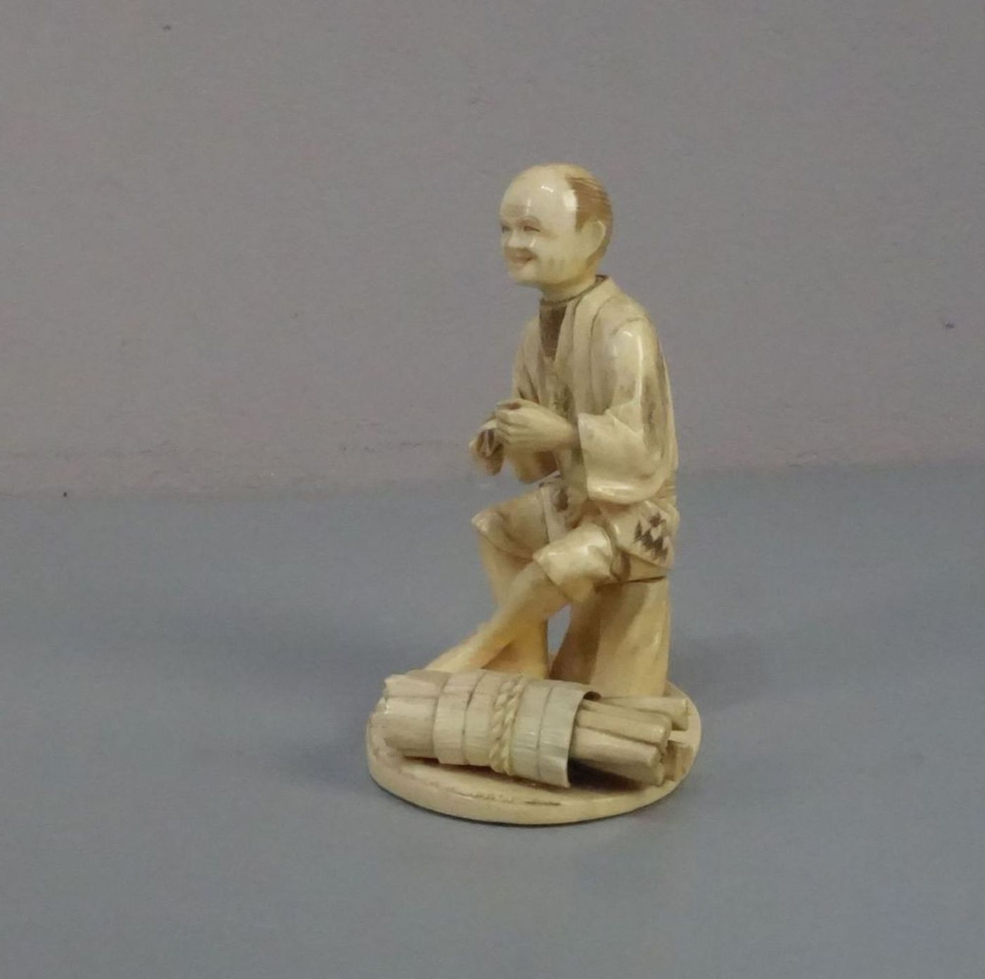 ELFENBEINFIGUR "Sitzender Mann mit Bündel" / Okimono Figur / ivory figure, Japan, wohl 19. Jh. (