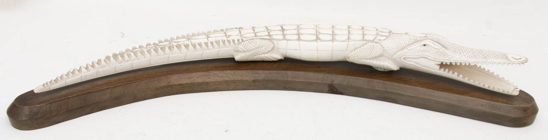 Elfenbeinschnitzerei - beschnitztes Krokodil auf Holzplinthe.