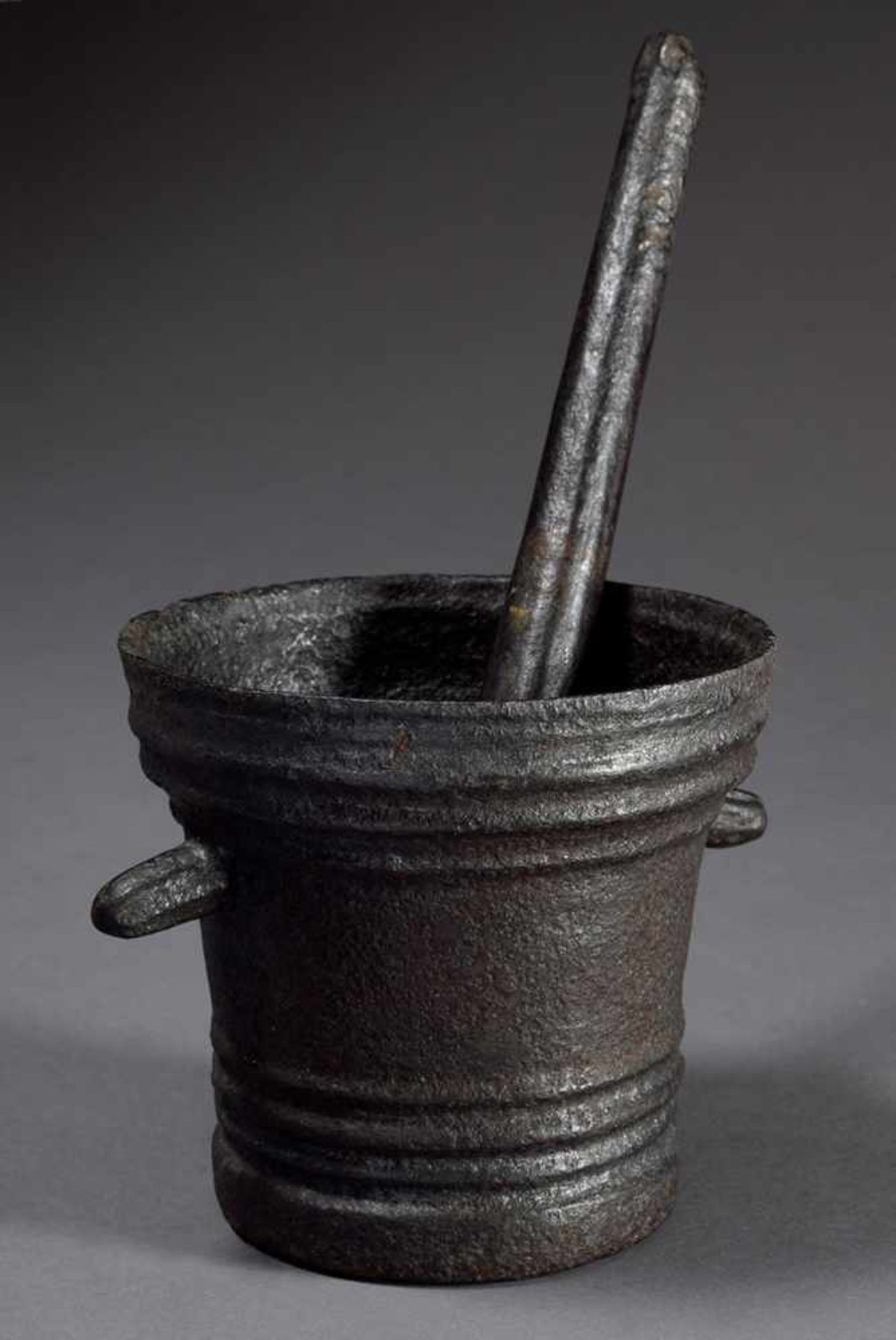 Cast-iron mortar with cylindrical body with longitudinal grooves and rod-shaped handles, probably