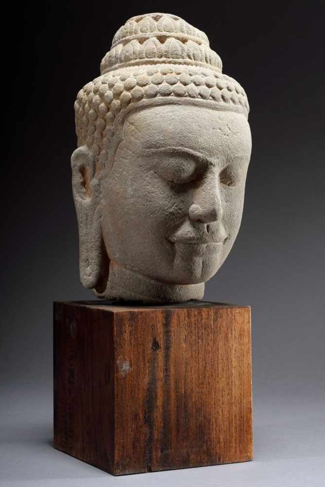 Sandstone Buddha head in Bayon style with stepped Unisha, on wooden base, Cambodia/Thailand, h. 30cm