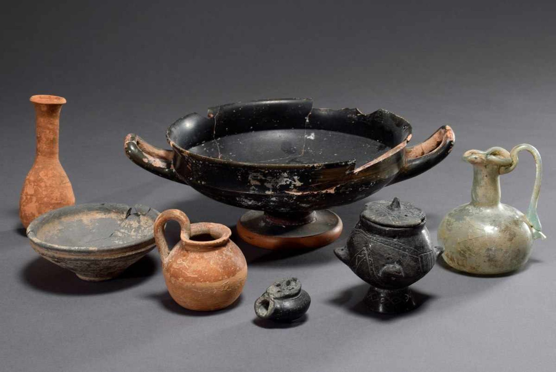 7 Various archaeological objects made of clay and glass: black Kylix (h. 9,5cm, Ø 20cm),