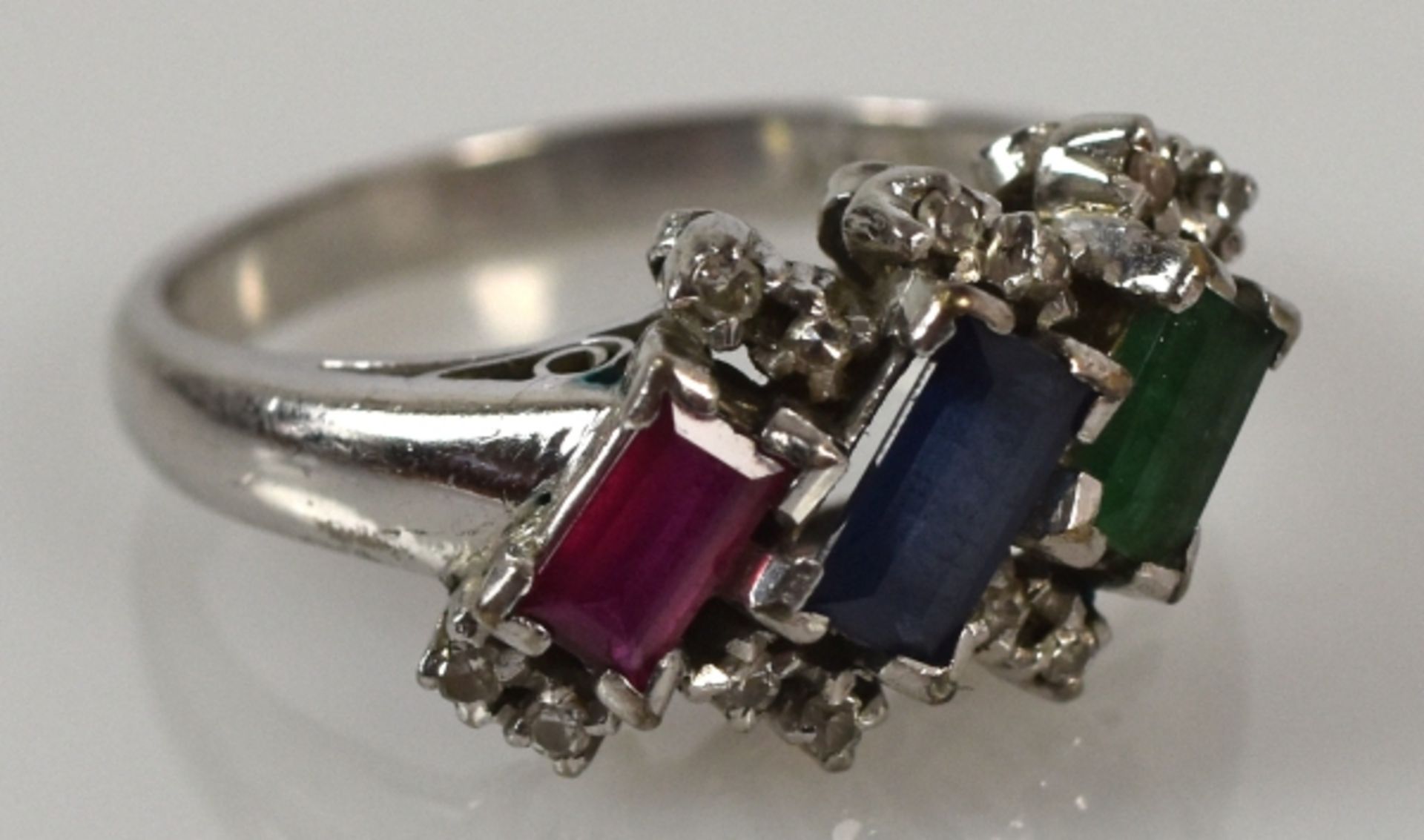 RING Schauseite mit geschliffenem Smaragd, Rubin, Saphir in Baguetteform, seitlich kleine Diamanten,