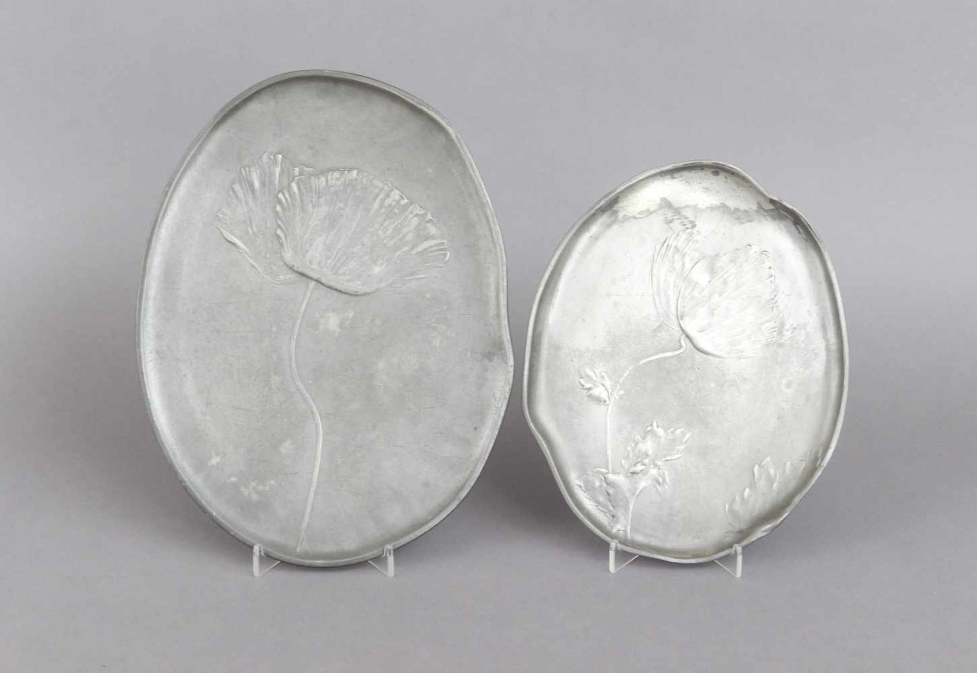 2 Zinnplatten mit MohnreliefKayserzinn, um 1900, ovale, leicht passige Form, L ca. 24cm bzw. 30