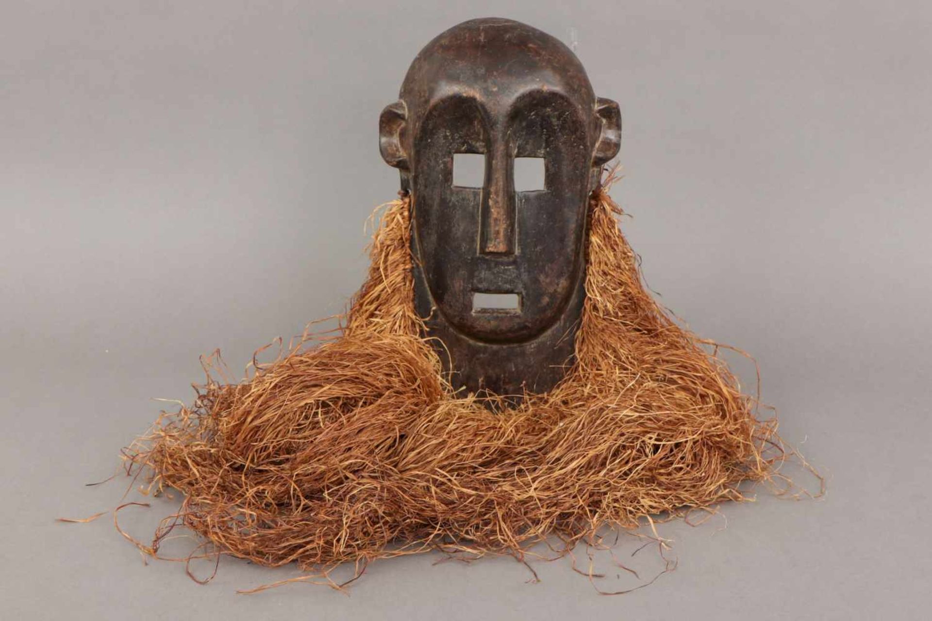 Afrikanische Tanzmaske der Lega, Kongo dunkel patiniertes Holz und Rafia (Bart), ovales Gesicht mit