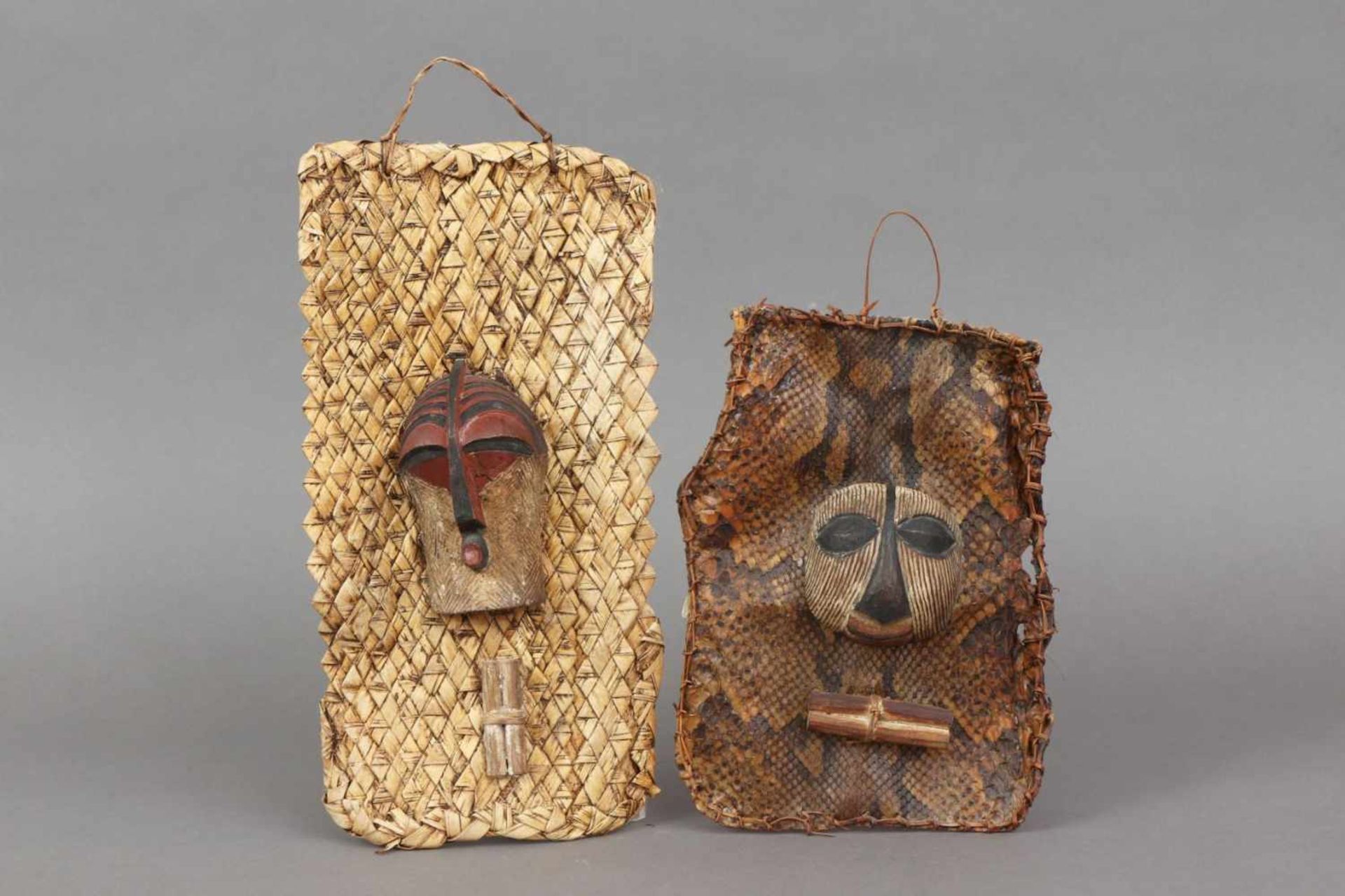 2 afrikanische Passport-Masken auf Schlangenhaut bzw. Rafia-Geflecht montiert, Kongo, Songye bzw.