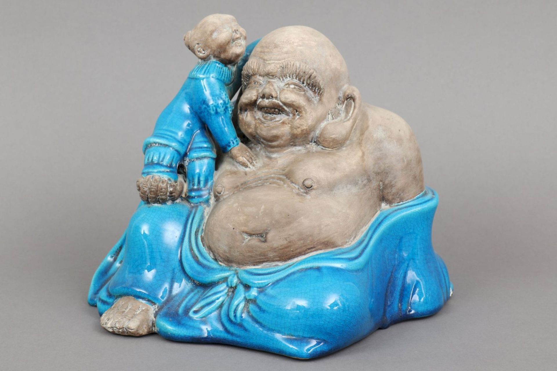 Chinesische BuddhafigurPorzellan, partiell blau glasiert, 20. Jhdt., lachende, sitzende Darstel