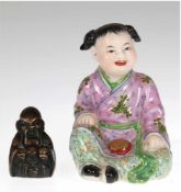 2 asiatische Figuren, Porzellanfigur "Sitzendes Kind", polychrom bemalt, Blockstempel undBronzefigur