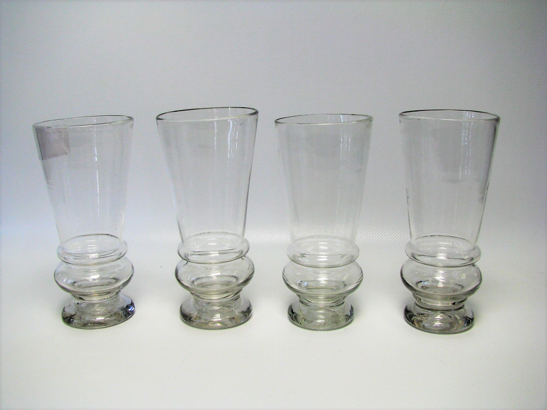 4 Becher, 19. Jahrhundert, farbloses Glas, h 14,5 cm, d 7 cm.