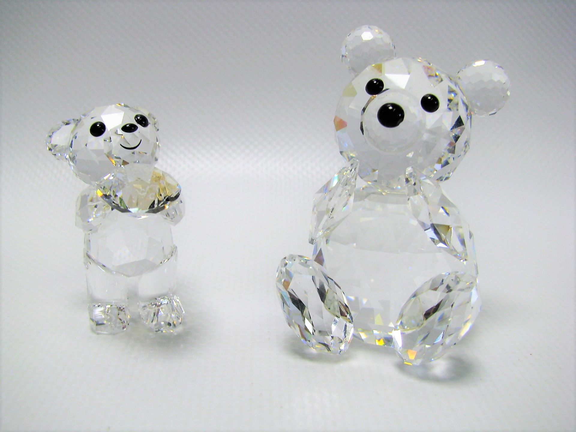 2 Bären, Swarovski, farbloses Kristallglas vielfach beschliffen, sign., h 4/5,5 cm.