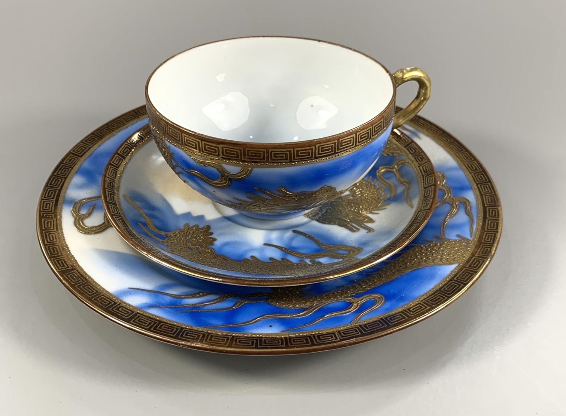 3tlg. Gedeck, Japan, 1930er Jahre, Porzellan, hellblau-weiß glasiert, goldgehöhtes Drachenmotiv,