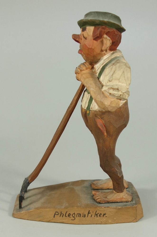 Holzfigur "Der Phlegmatiker", handgeschnitzt, 20.Jh., barfüßiger Mann, träge auf seine Heugabel