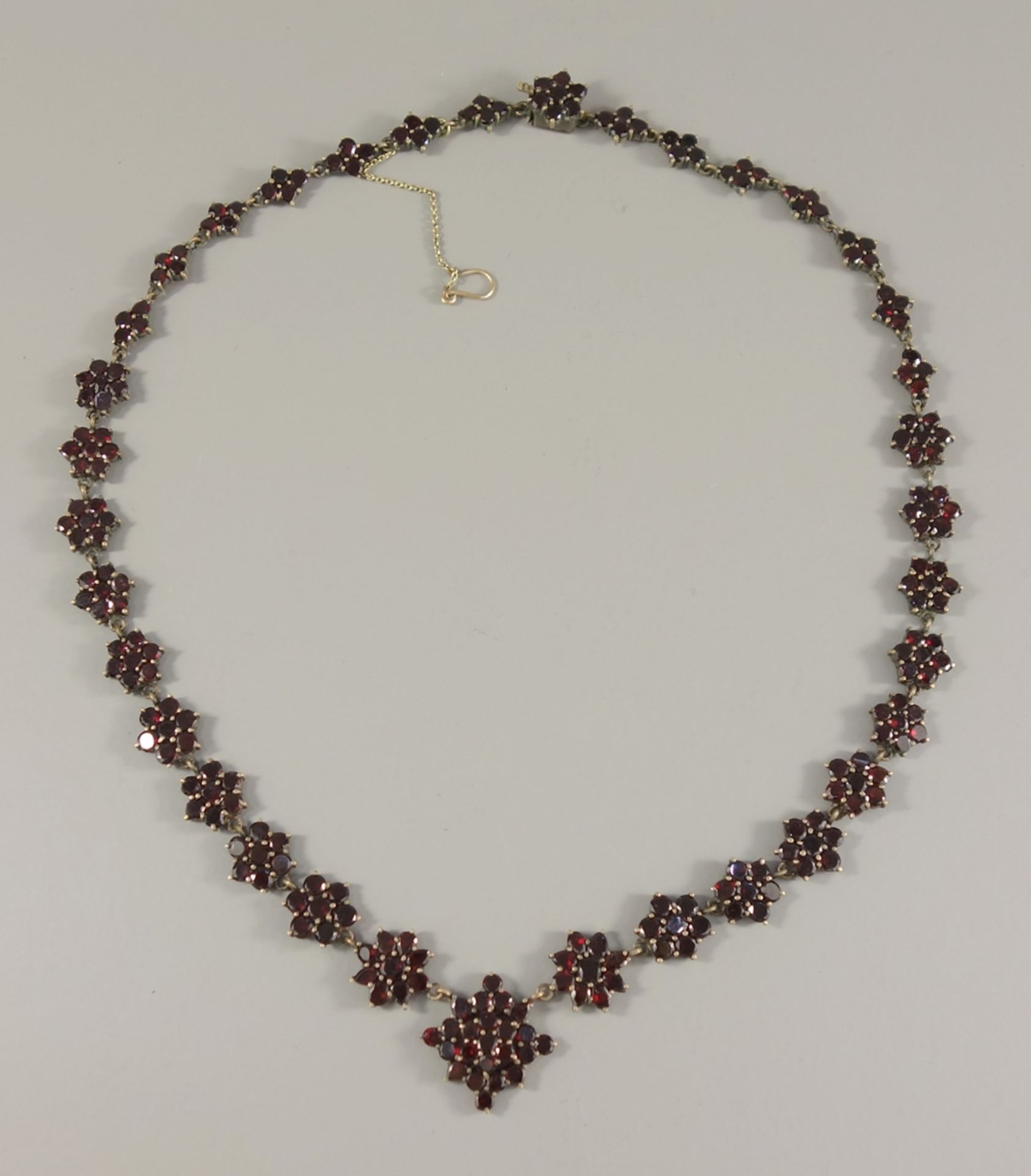 Granatcollier mit Sicherheitskettchen, Böhmen um 1900, Tombak, verjüngende Blüten, Steckschloss mit