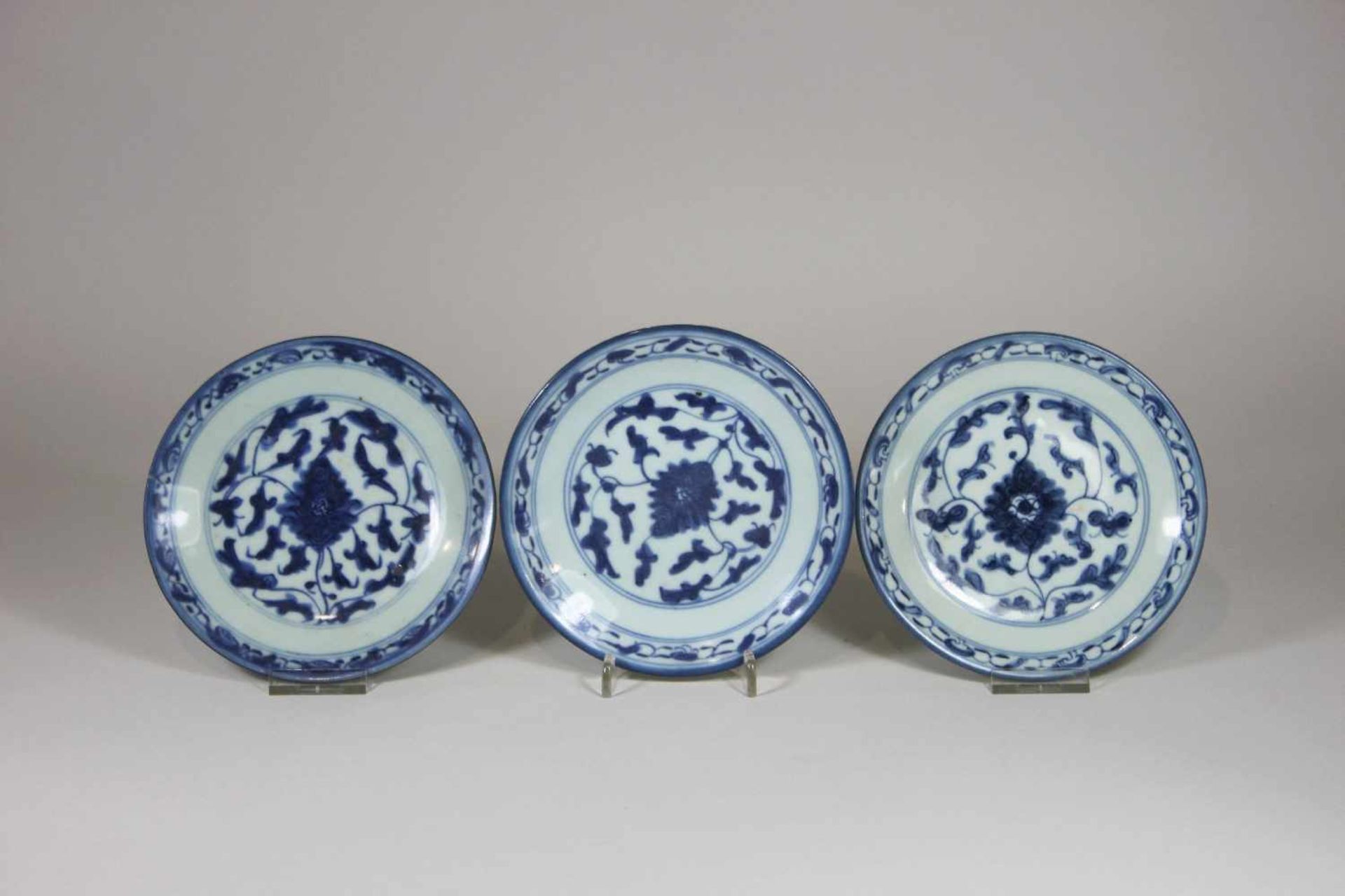 Drei Teller, China, blaue Marken unter Glasur, mit blauen Blumen verziert, D.: 15 cm, Chips am